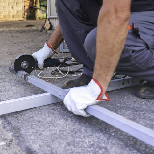 Active senior using an angle grinder to grind a metal piece that he will use to repair his shed